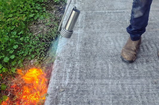Weed burner clearing weeds along the edge of a concrete path on an Australian property